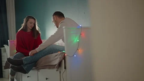 Couple sharing item on bed with one person leaning forward to hand over object Vídeo Stock 346644469