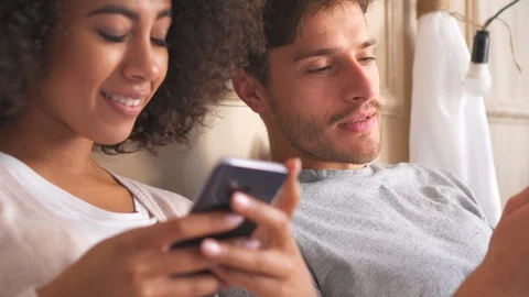 Couple sharing mobile phone in bed Stock Footage 98322248