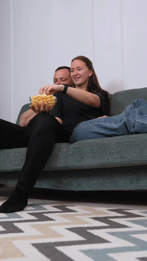 Couple sharing popcorn while watching movie on sofa Stock Footage 317444581