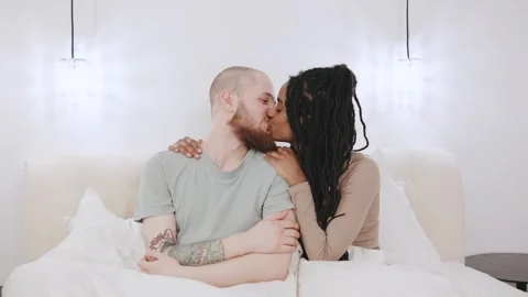 Couple sharing a tender moment while cuddling in bed with soft lighting Stock Footage 307411064