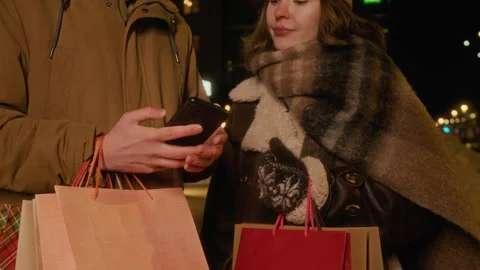 Couple with Shopping Bags Using Mobile App on Winter Street Stock Footage 342014647