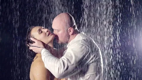 Couple in the shower. naked girl and her man in a white wet shirt. he holds her Stock Footage
