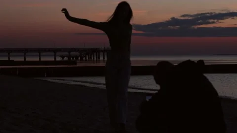 Couple silhouette on beach sunset evening, man taking photo, female woman posing Stock Footage 174694857