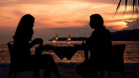 Couple silhouettes having dinner on beach at sunset Stock Footage 79085993