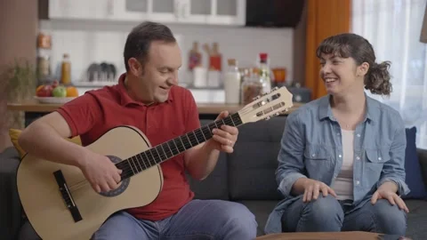 Couple singing together while playing the guitar at their home. Stock Footage 148254954