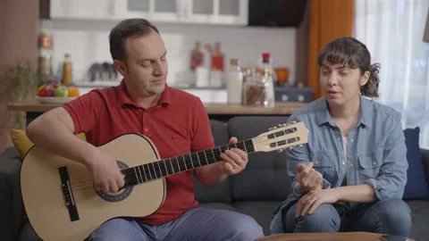 Couple singing together while playing the guitar at their home. Stock Footage 148255088