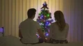 The couple sit on the bed near the christmas tree 4k or 4k+ Resolution