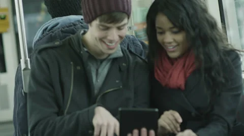 A couple sit on a bus and have a good time playing with their tablet computer Stock Footage 34017564