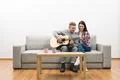 The couple sit on the sofa and play the guitar on the white wall background Photo