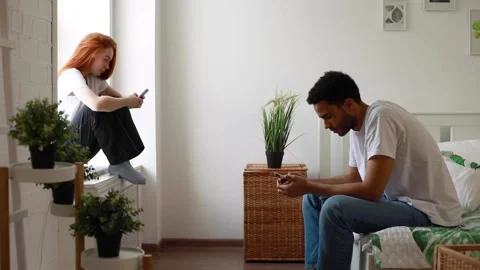 A couple sit stuck each in their smartphone in the bedroom. Stock Footage 181538154