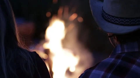 Couple sits by fire at dawn rack focus to fire Stock Footage 56564539