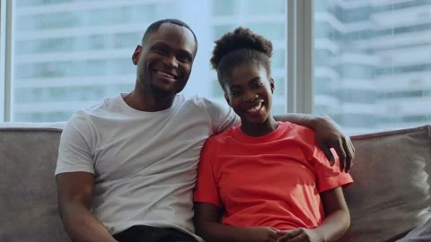 A couple sits on the sofa and the man puts his hand on her shoulder, new step in Stock Footage 285322105
