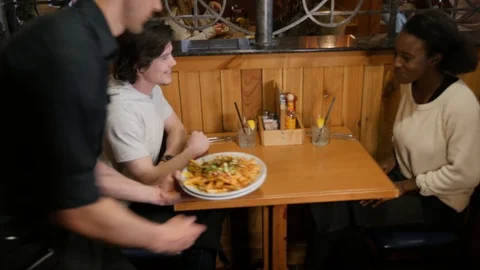 Couple sits at table server brings plate of hillbilly french fries to table c Stock-Footage 89369006