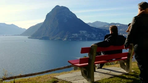 Couple Sitting and Hugging on a Bench with Lake Lugano and Mountain View Stock Footage 194011874
