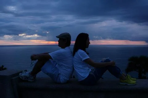 Couple Sitting Back-to-Back at Sunset Stock Photos