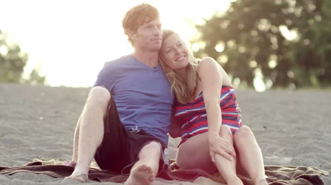 A couple sitting on the beach and looking into the distance Stock Footage 57402402