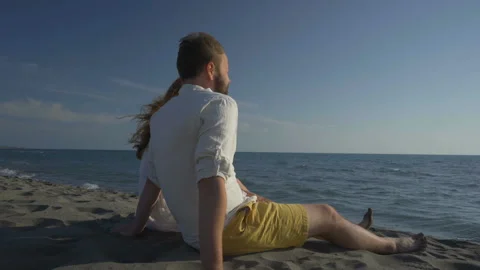 Couple sitting on the beach and looking at the sea Stock Footage 119113601