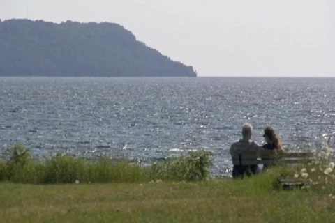 Couple sitting at beach, cliffs in bkgd Stock Footage 148856