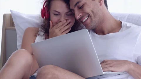 Couple sitting on the bed. Man and woman watching to a laptop. Stock Footage 107736046