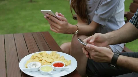 Couple sitting behind the table. They are using smartphones and eating tortilla Video stock 51441083