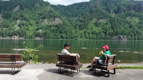 Couple sitting bench, admiring view of mountain and river Stock Footage 245295968