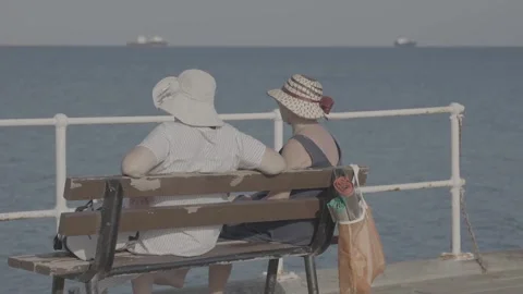 A couple sitting on a bench by the beach in Paphos, Cyprus Stock Footage 344056517