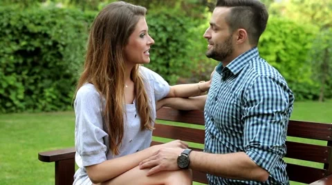 Couple sitting on the bench in the garden. They are talking and flirting. Stock Footage 51440887