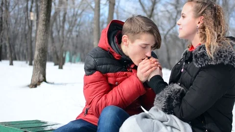The couple is sitting on a bench in the winter. the guy is heating the girl Stock-Footage 88374736