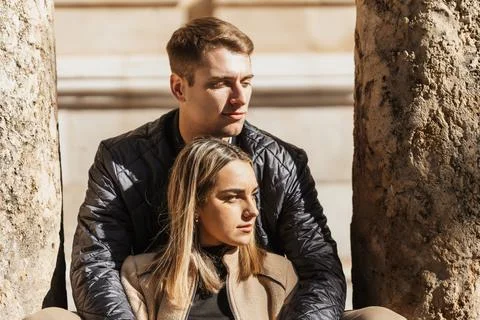 A couple sitting between two columns bask in the autumn sunshine Stock Photos