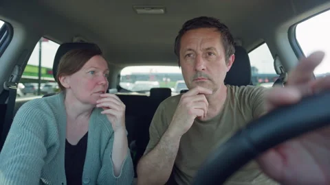 Couple sitting in car looking thoughtful and talking while driver considers.. Stock Footage 334796495