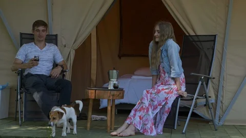 A couple sitting on chairs, talking, drinking coffee, playing with the dog Stock Footage 126644804