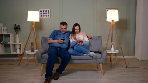 Couple sitting on the couch and playing on mobile phones Stock-Footage 126852574