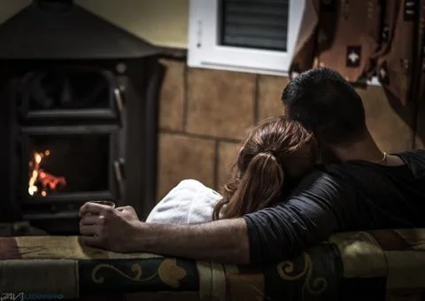 Couple sitting on a couch looking at the fire Stock Photos
