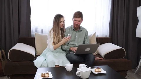Couple is sitting on the couch sofa at home Look at the laptop screen and smile Stock Footage 74605574