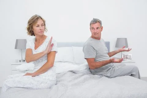 Couple sitting on different sides of bed having an argument Stock Photos