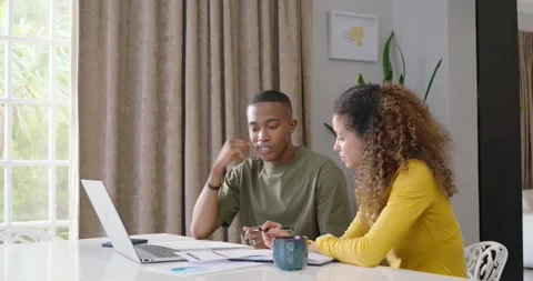 Couple sitting at dining table checking papers and laptop, reviewing, pointing, Stock Footage 337289048