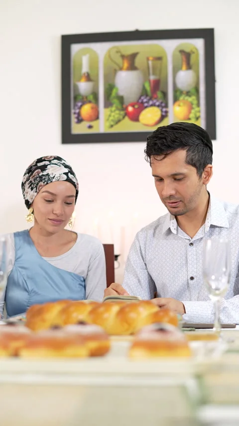 Couple sitting at dining table with traditional Hanukkah food. Stock Footage 287136733