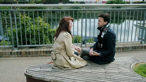 Couple sitting down having a conversation outdoors city Stock Footage 130597081