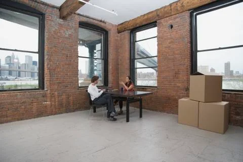 Couple sitting in an empty loft apartment Stock Photos
