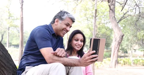Couple sitting on fallen tree and using mobile phone at park Stock Footage 169913032