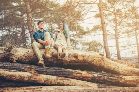 Couple sitting on fallen tree trunk Stock Photos