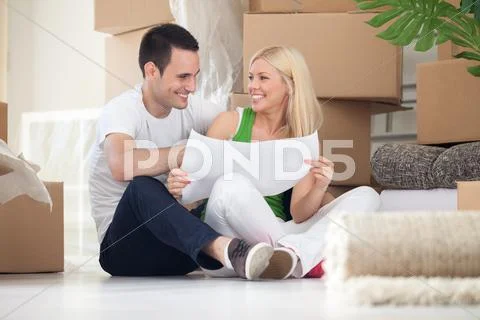 Couple sitting on floor looking at house plans Stock Photos
