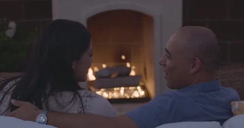 Couple sitting in front of fireplace and talking to each other Stock Footage 83187201