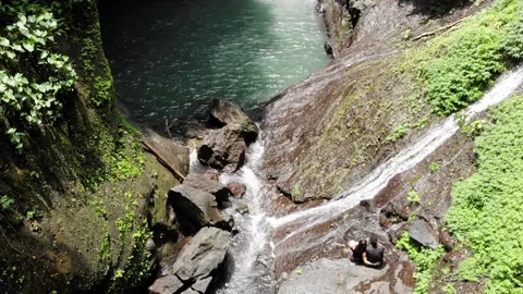 Couple Sitting in Front of Waterfall in Bali Indonesia, Aerial View Stock Footage 142304580