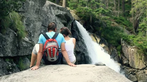 Couple sitting in front of a waterfall Stock Footage 7907582