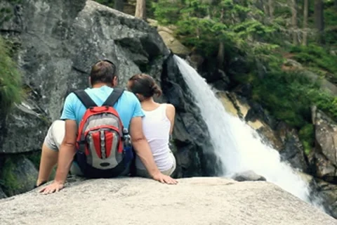 Couple sitting in front of a waterfall Stock Footage 7907587