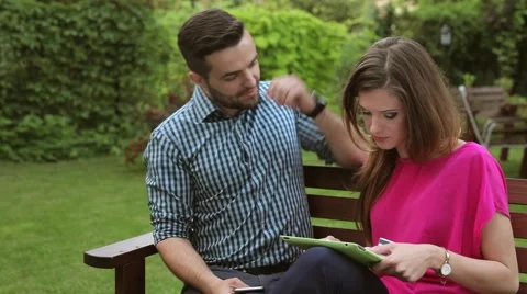 Couple sitting in the garden,using tablet and smartphone.  looking into camera Stock Footage 51441764