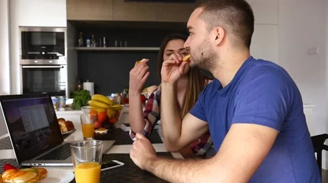 Couple sitting in the kitchen. They are talking and eating cookies Stock Footage 61859596