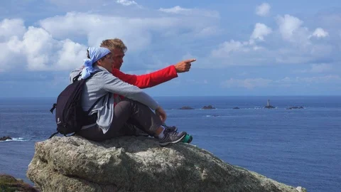 Couple sitting on a large stone observes the view at Land's End Stock Footage 125417477