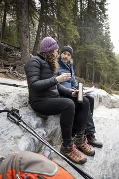 Couple sitting looking at map and having drink on rock Fotos Stock